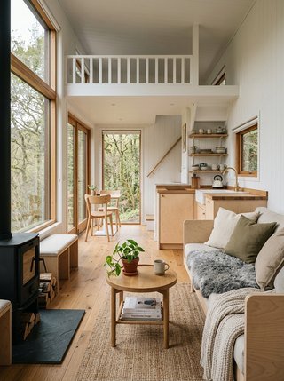 Cozy Scandinavian tiny house living area featuring a sheepskin throw and large south-facing windows