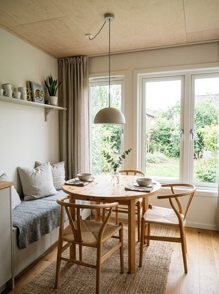 Compact Scandinavian tiny house dining area, illuminated by a pendant lamp and surrounding windows
